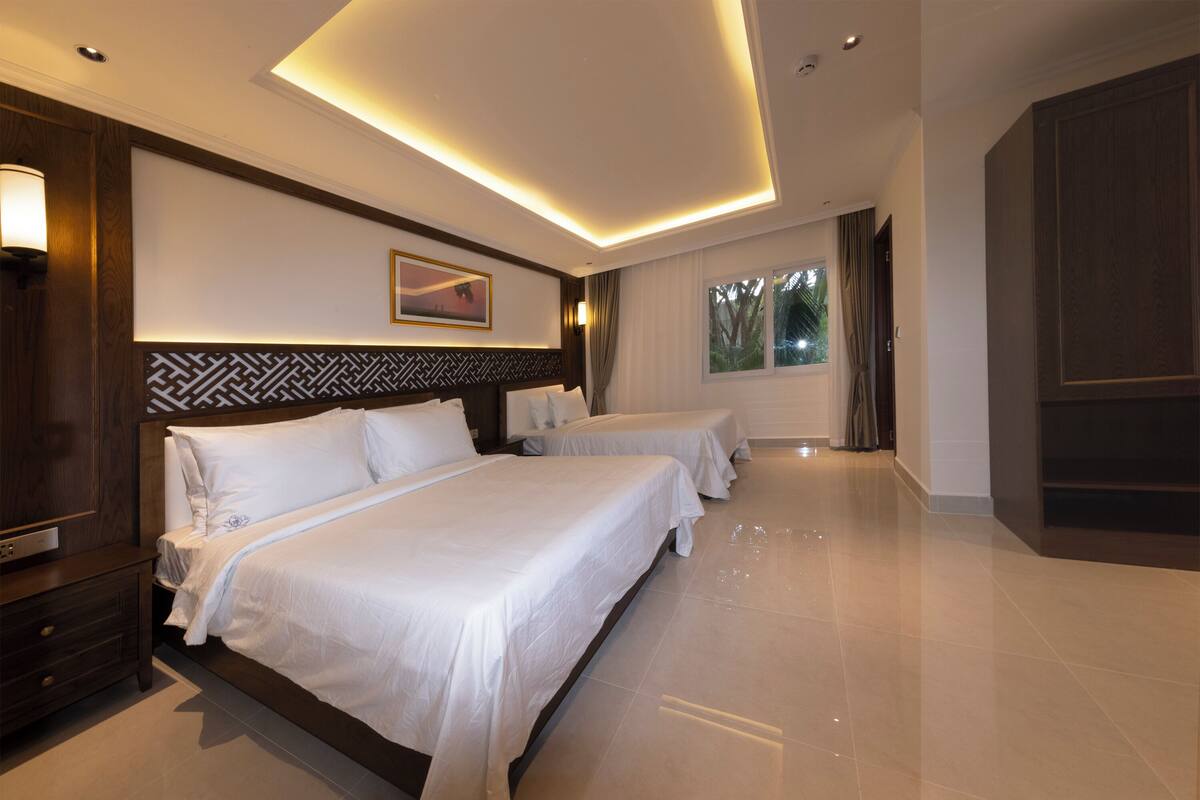 A hotel room with two beds, a large window, and a modern design.