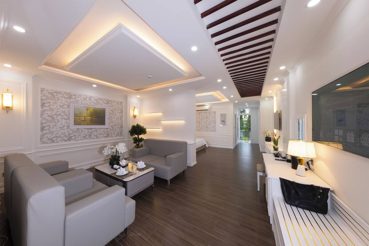 A modern hotel lobby with a seating area, a reception desk, and a hallway leading to other rooms.