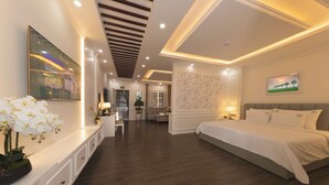 Une chambre d’hôtel moderne dotée d’un grand lit, d’un coin salon avec une table et des chaises, et d’un mur décoratif agrémenté d’un tableau encadré.