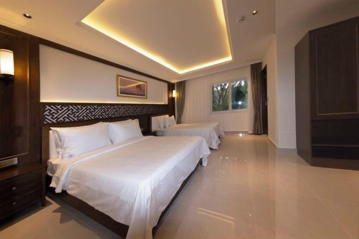 Habitación de hotel con dos camas, un ventanal grande y un diseño moderno en el techo.
