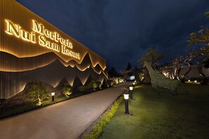 The exterior of Niu San Resort with a prominent illuminated sign, a well-lit pathway, and landscaped greenery. - MERPERLE NUI SAM RESORT (Chau Doc)