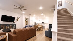Ein modernes Wohnzimmer mit einer braunen Ledersofa, einem flachbildfernseher an der Wand und einem Deckenventilator.