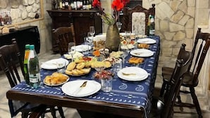 A dining area with a stone wall, wooden furniture, and a table set for a meal. - Hotel bani (Kutaisi)