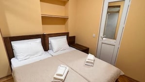 A hotel room with a bed, two pillows, a bedside table, a mirror, and an air conditioning unit. - Hotel bani (Kutaisi)