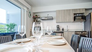 A dining area with a table set for four, including wine glasses, plates, and cutlery. - Casago | Beach & Marine Design Condo in Jacó (Jaco)