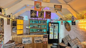 En bar med træmøbler, et neonskilt og diverse flasker spiritus.