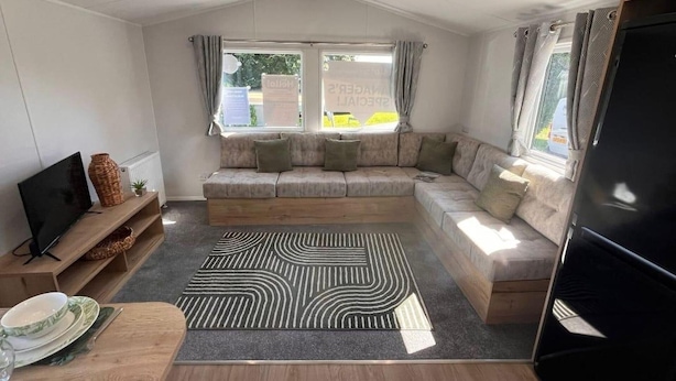 En hyggelig stue med sofa, fjernsyn og spiseplads.