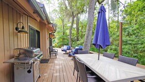 Une terrasse extérieure équipée d’un barbecue, d’une table à manger et de chaises.