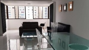A modern living room with a glass coffee table, a sofa, and a chair.