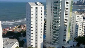 A high-rise hotel with multiple floors, balconies, and a view of the beach and ocean.