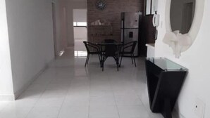 A modern kitchen with a dining area, featuring a brick wall, a clock, and a refrigerator.