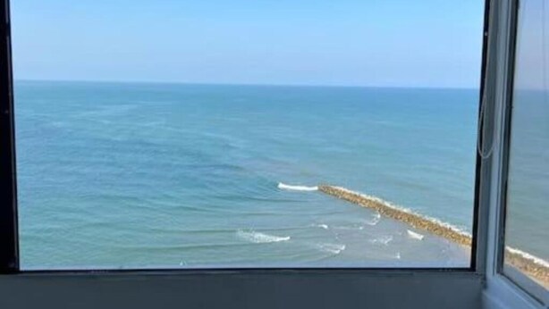 A view of the ocean through a window with a clear sky.