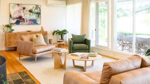 A modern living room with a sofa, armchair, coffee table, and a painting on the wall.