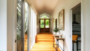 A hallway with wooden flooring, a dining table with chairs, and a staircase leading to another room.