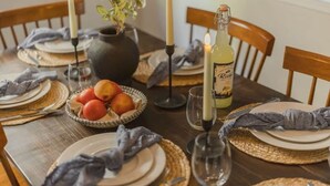 A dining table set with plates, cutlery, a candle, a bottle of wine, and a bowl of fruit. - The Incline Cabin, Hot Tub | Fireplace | Arcade | 5min to Diamond Pk (Incline Village)