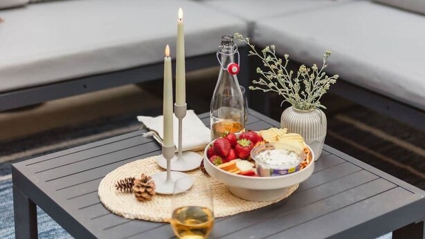 A cozy outdoor seating area with a table set for a meal, featuring a candle, a bottle, and a bowl of fruit. - The Incline Cabin, Hot Tub | Fireplace | Arcade | 5min to Diamond Pk (Incline Village)