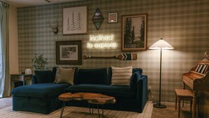 A cozy living room with a dark blue sofa, a wooden coffee table, a standing lamp, and a piano. - The Incline Cabin, Hot Tub | Fireplace | Arcade | 5min to Diamond Pk (Incline Village)