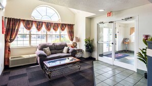 A lobby with a sofa, a coffee table, a lamp, a potted plant, and an exit sign. - Motel 6 Chattanooga, TN - Downtown (Chattanooga)