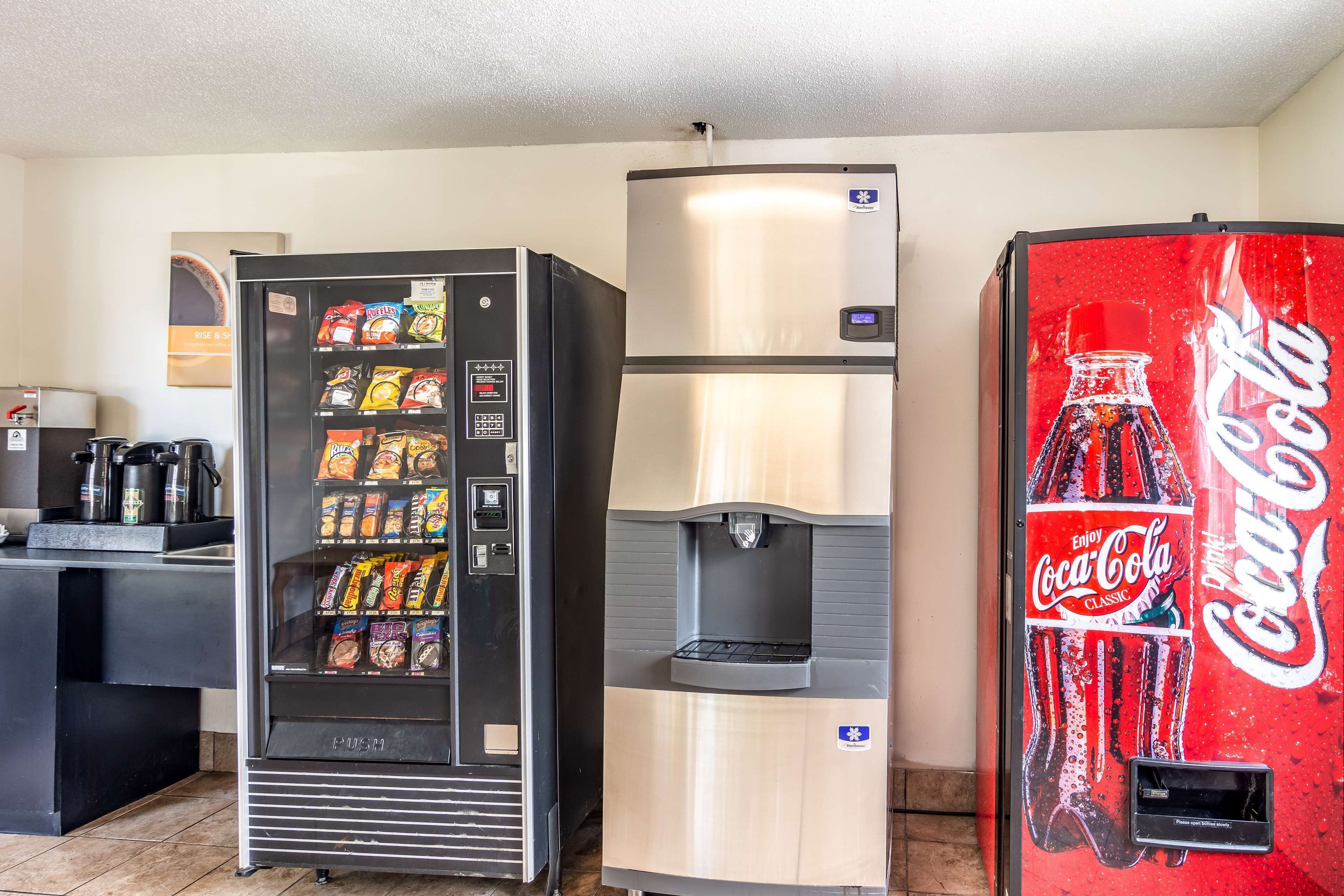 A vending machine with snacks, a water dispenser, and a Coca-Cola machine in a commercial setting.