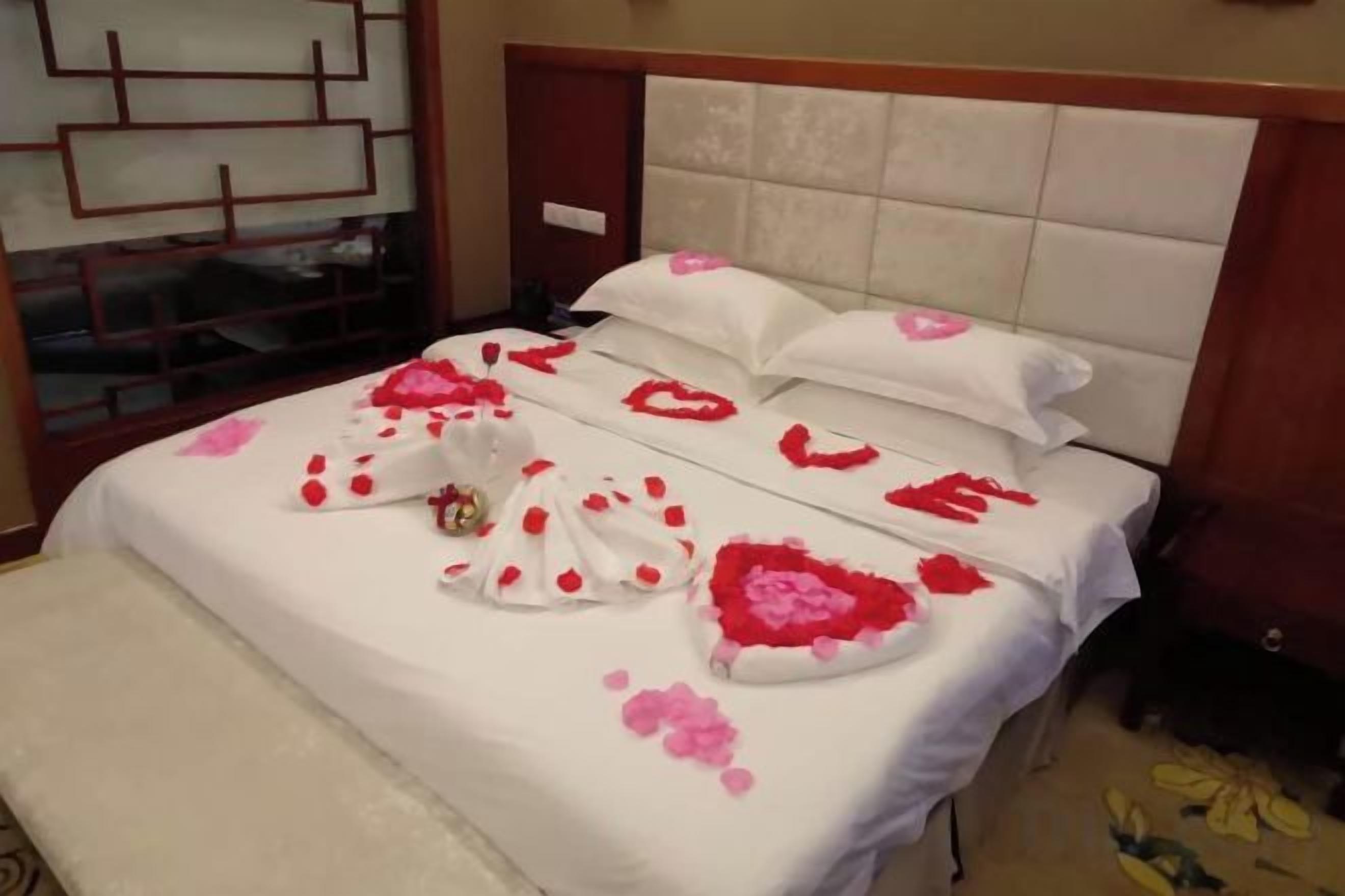 A bed with a white headboard and pillows, a bench, and a small table with a decorative item.