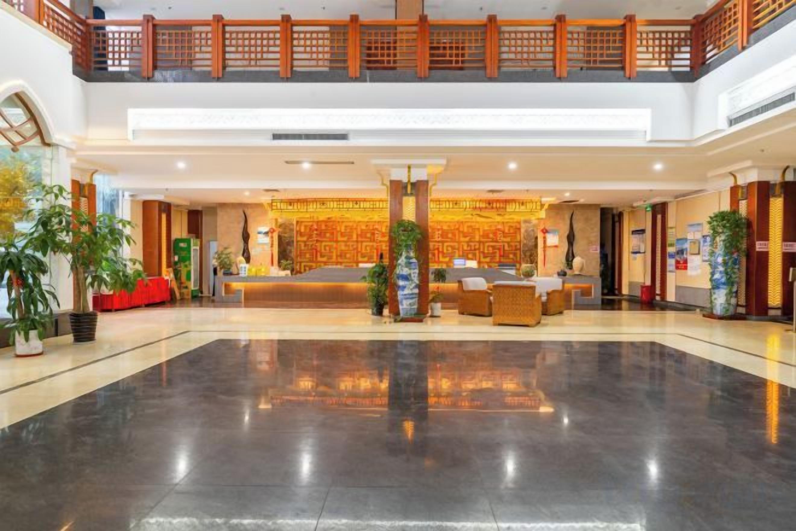 Eine großzügige Lobby mit einer Rezeption, einer Sitzecke und einem Balkon im zweiten Stock.