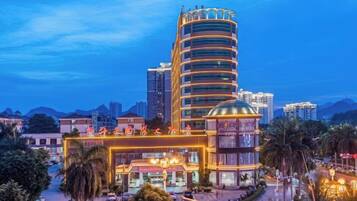 A multi-story hotel with a distinctive curved facade, a dome structure, and a well-lit entrance.