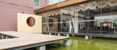 A courtyard with a wooden deck, a circular structure, and a building with large windows and a balcony.