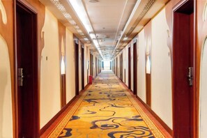 A hotel hallway with doors on both sides, carpeted with a patterned design, and overhead lighting. - Pingguo International Hotel (Pingguo)