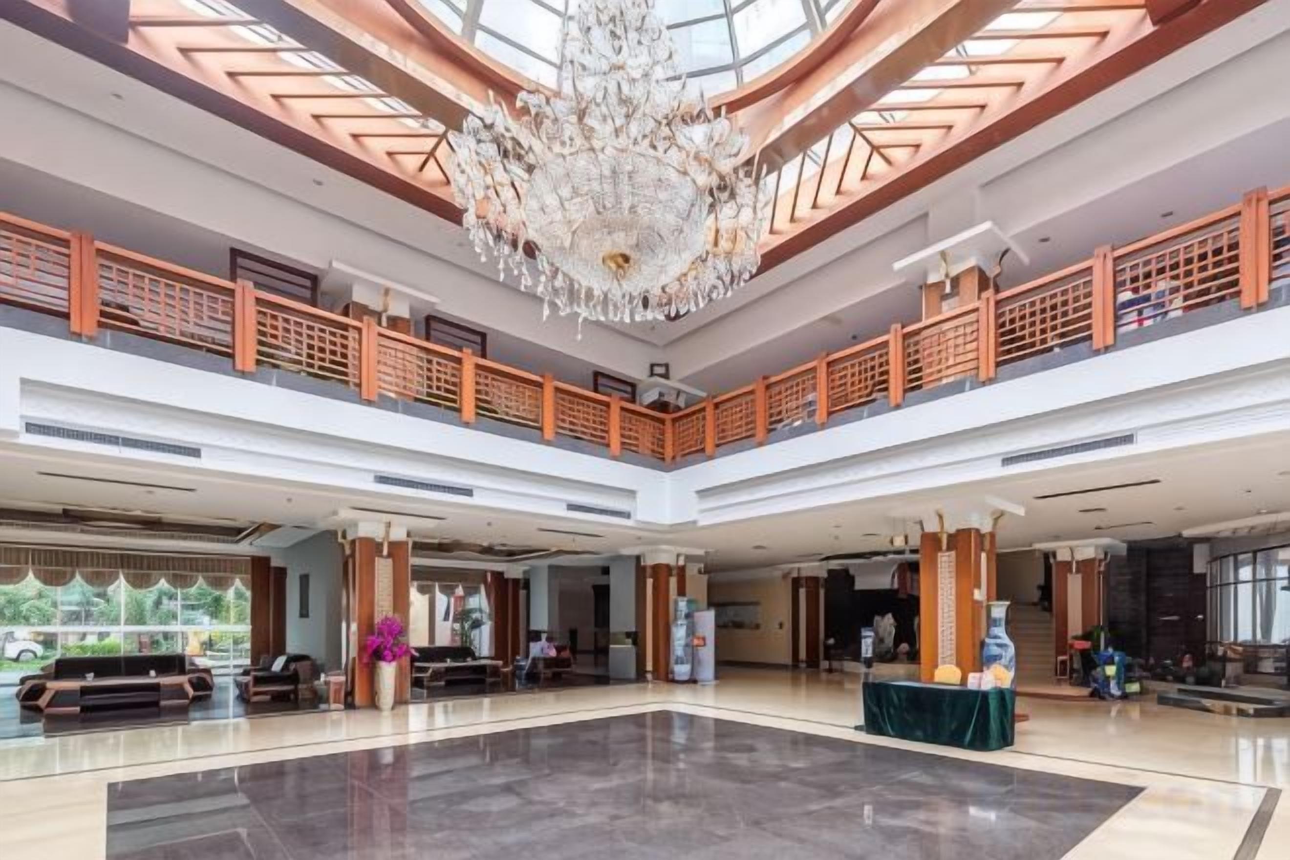 A spacious lobby with a high ceiling, a grand chandelier, and a central seating area.