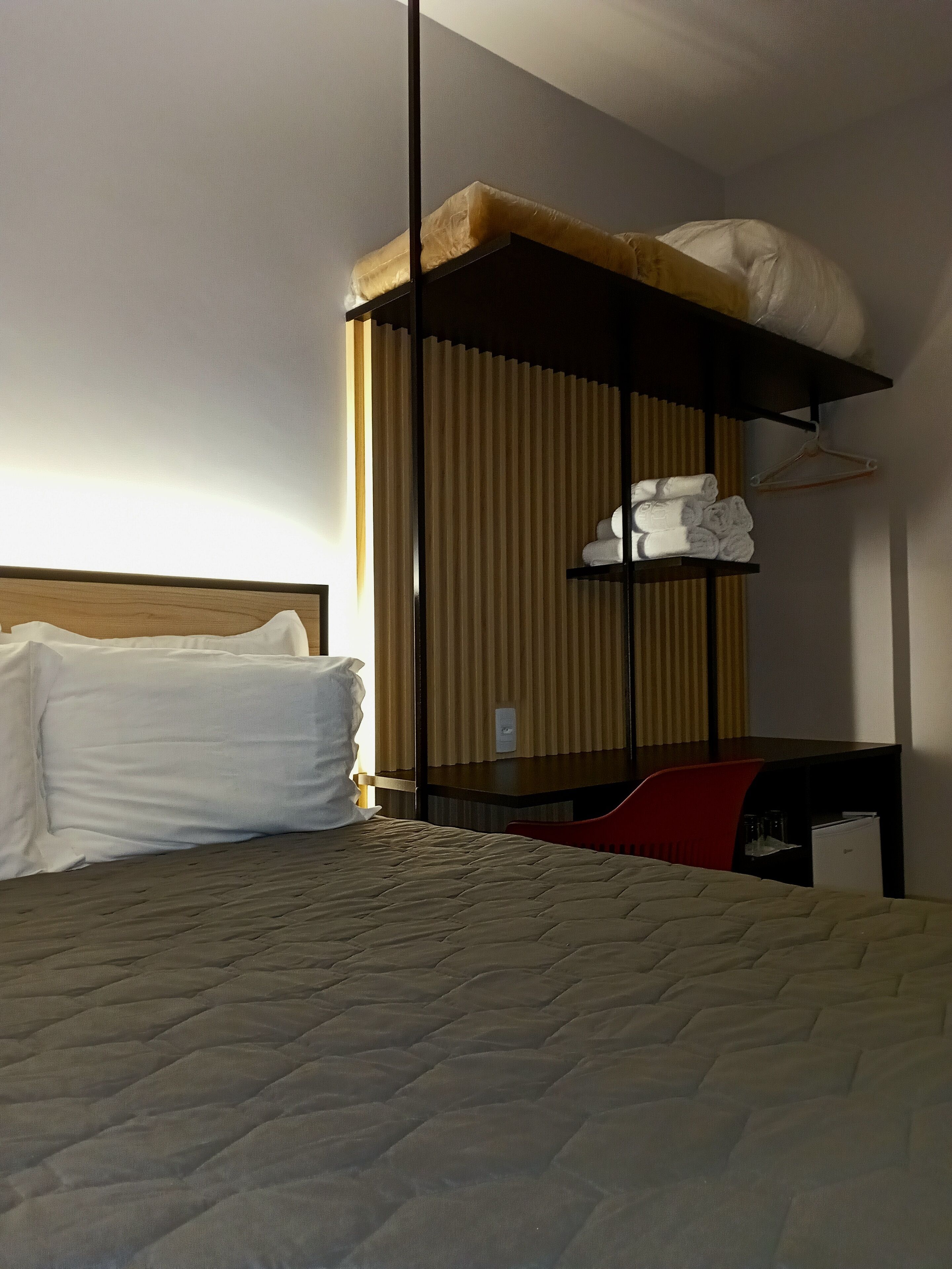 A hotel room with a bed, a bunk bed, a desk, and a chair.