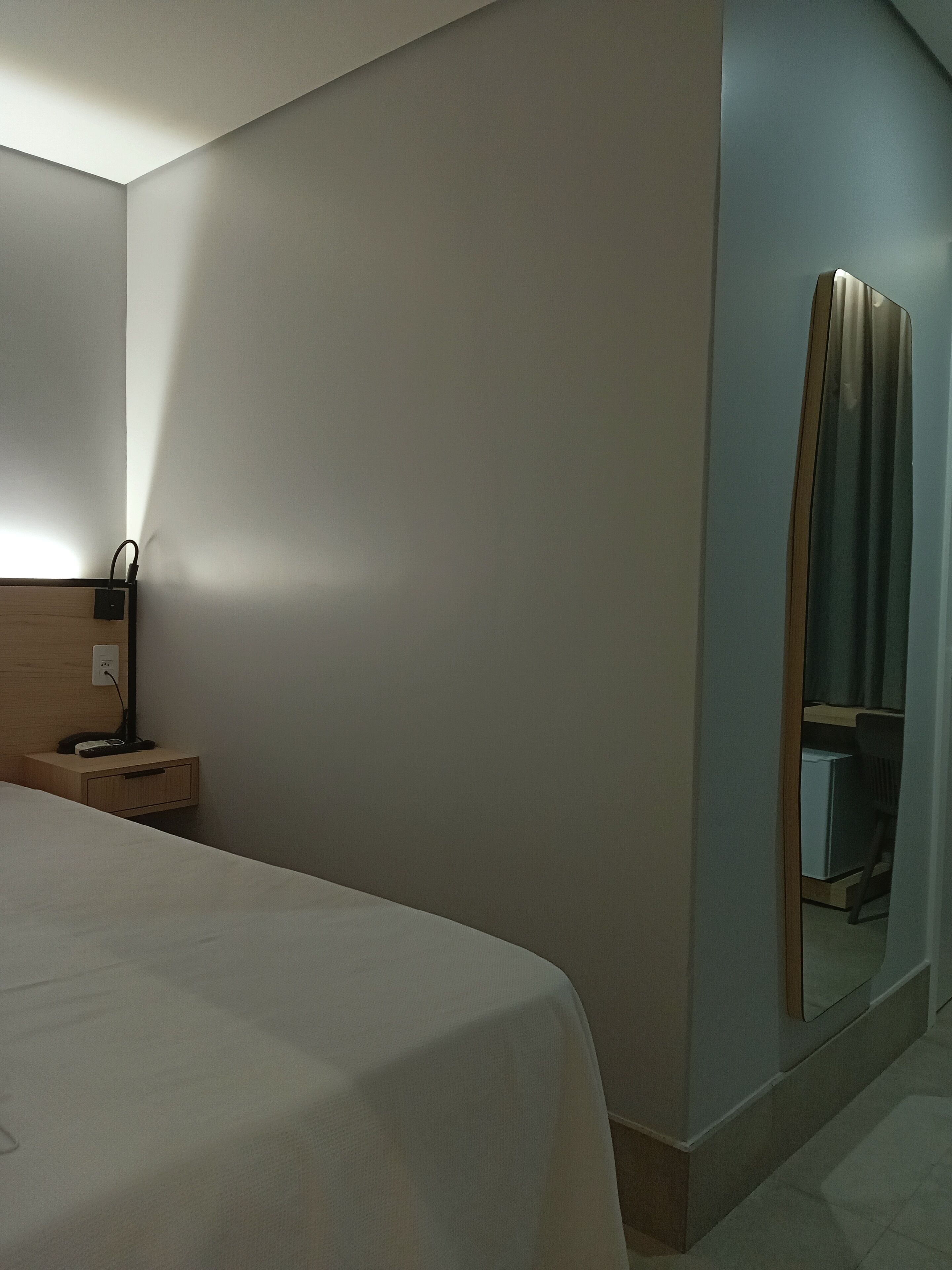 Ein Hotelzimmer mit Bett, Nachttisch und Spiegel.