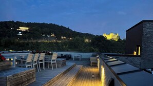 A wooden deck with seating areas and a view of a hill with buildings. - Stylish Seaview 4 Beds Central Apartment Sorenga (Oslo)