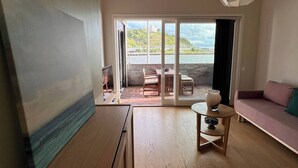 A spacious living area with a wooden floor, a sofa, a table with a vase, and a view of a balcony with outdoor furniture. - Stylish Seaview 4 Beds Central Apartment Sorenga (Oslo)