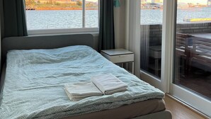 A bedroom with a large bed, a small bedside table, and a view of a waterfront. - Stylish Seaview 4 Beds Central Apartment Sorenga (Oslo)