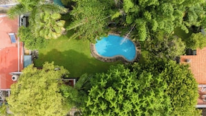An aerial view of a property with a swimming pool surrounded by lush greenery and a red-roofed building. - Family-Friendly Oasis with Pool (Cuernavaca)