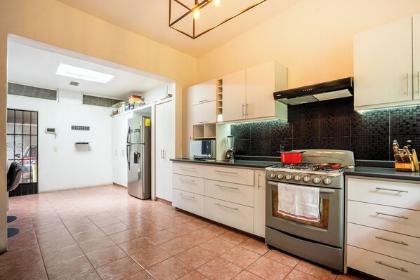 A modern kitchen with white cabinets, a stainless steel stove, and a black tiled backsplash.