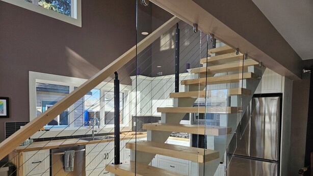 A modern kitchen with a stainless steel refrigerator, wooden staircase, and a glass railing. - Amazing Peace Chalet Oasis - Rockies Doorway / Easy 20 min commute Calgary South (High River)