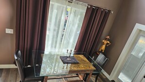 A dining area with a glass table, dark brown curtains, and a statue. - Amazing Peace Chalet Oasis - Rockies Doorway / Easy 20 min commute Calgary South (High River)