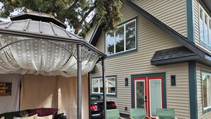 A covered outdoor seating area with a gazebo, a wooden deck, and a house with beige siding and red trim. - Amazing Peace Chalet Oasis - Rockies Doorway / Easy 20 min commute Calgary South (High River)