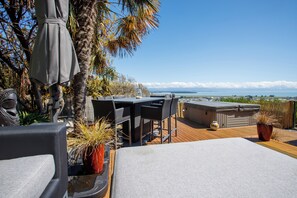 A rooftop terrace with a table and chairs, a hot tub, and a view of the ocean. - Sunset Heights - Nelson Holiday Home (Nelson)