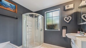 A modern bathroom with a glass-enclosed shower, a white sink, and a large mirror. - Sunset Heights - Nelson Holiday Home (Nelson)