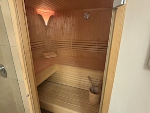 A sauna with wooden walls and benches, a sloped floor, and a wooden bucket. - Fantastic Apartment in the Kitzbuhel Alps (Mittersill)