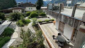 A wooden deck with outdoor seating, surrounded by greenery and a mountain view. - Fantastic Apartment in the Kitzbuhel Alps (Mittersill)