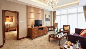 A modern hotel room with a flat-screen TV, wooden furniture, a dining table with breakfast, and a large window with curtains. - Hainan Guest House No.1 Building (Haikou)