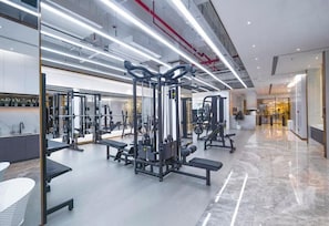 A modern gym with various exercise equipment, a marble floor, and a clean, well-lit interior.