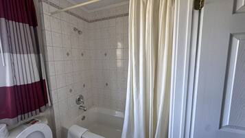 Un baño con bañera, inodoro y cortina de ducha.