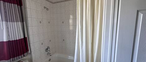 Un baño con bañera, inodoro y cortina de ducha.