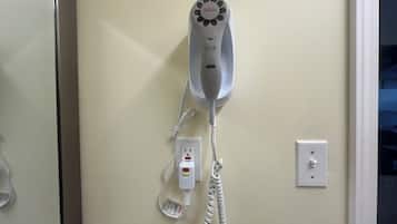 A hair dryer mounted on a wall with a power cord and a plug.