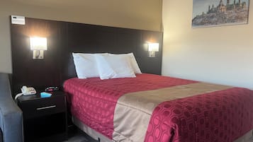 A hotel room with a large bed, two bedside tables, a nightstand, a clock, and a painting on the wall.