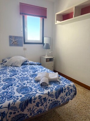 A bedroom with a bed, a nightstand, a lamp, a window with blinds, and a wall decoration. - Cozy 3 bedroom detached house near San Agustin (San Bartolome de Tirajana)